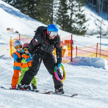 Ein Skilehrer fährt gemeinsam mit zwei kleinen Kindern im Kinderland Ski  | © Schischule Gargellen